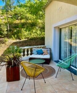 Terrasse devant une maison avec un fauteuil et une plante aux Terrasses de Valerian