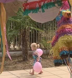 Une enfant marche en tenant des ballons gonflés pour une fête