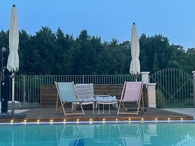 A la nuit tombée, des transat et des parasols pliés, au bord d'une piscine