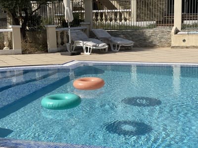 Deux bouées flottent sur une piscine? Dans le fond, 2 transats sont posés eau bord